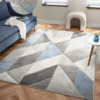 Orbit Alto rug featuring layered blue shades and a smooth modern texture, shown laid flat in a bright contemporary room.