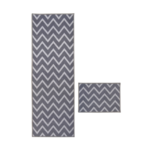Grey flatweave rug with chevron design on white background.